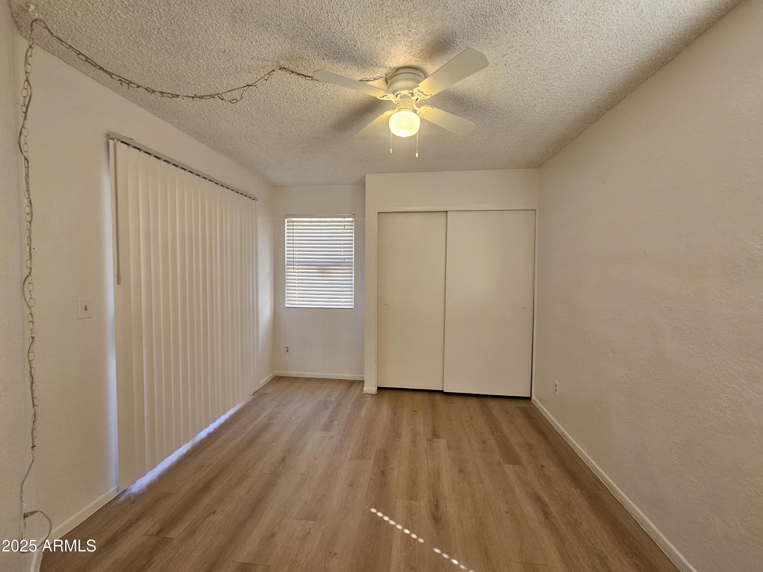 1370 South Price Road, Unit 101 Tempe, AZ 85281 - Photo 9 of 11 an empty room with wooden floor and windows