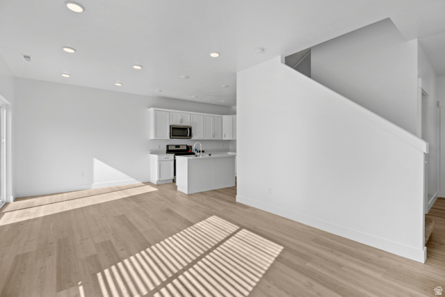 1271 West 500 South Logan, UT 84321 - Photo 4 of 26 Open-concept main level featuring wood-finish flooring, recessed lighting, a sliding glass door, white cabinetry, and an integrated kitchen island with a sink