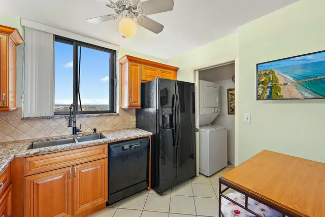 a kitchen with stainless steel appliances granite countertop a sink cabinets and a refrigerator