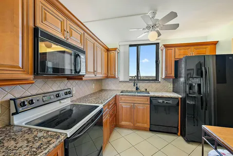 a kitchen with stainless steel appliances granite countertop a sink a stove a refrigerator cabinets and a dining table