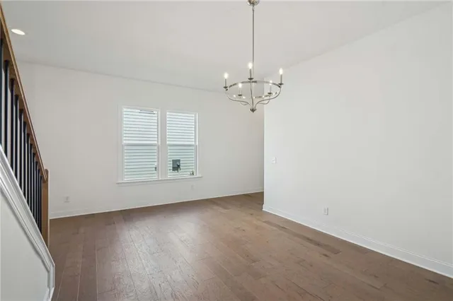 an empty room with wooden floor chandelier and windows