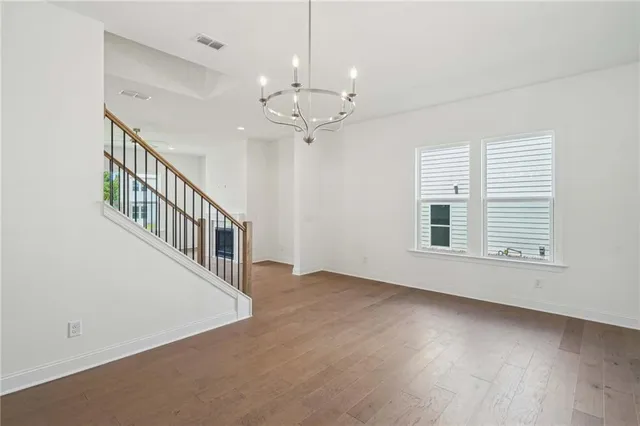 an empty room with chandelier fan windows and a ceiling fan