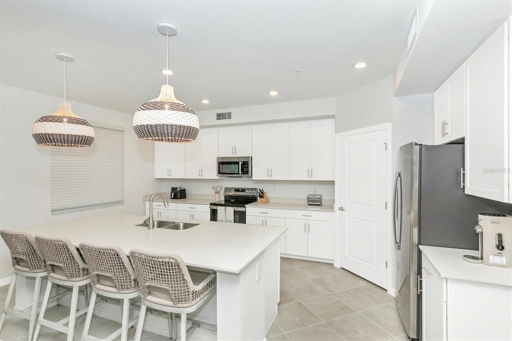 12625 Radiance Court, Unit 102 Venice, FL 34293 - Photo 11 of 99 a kitchen with stainless steel appliances a sink a stove a refrigerator and cabinets