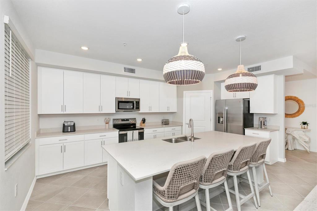 12625 Radiance Court, Unit 102 Venice, FL 34293 - Photo 13 of 99 a kitchen with stainless steel appliances a table chairs and a chandelier