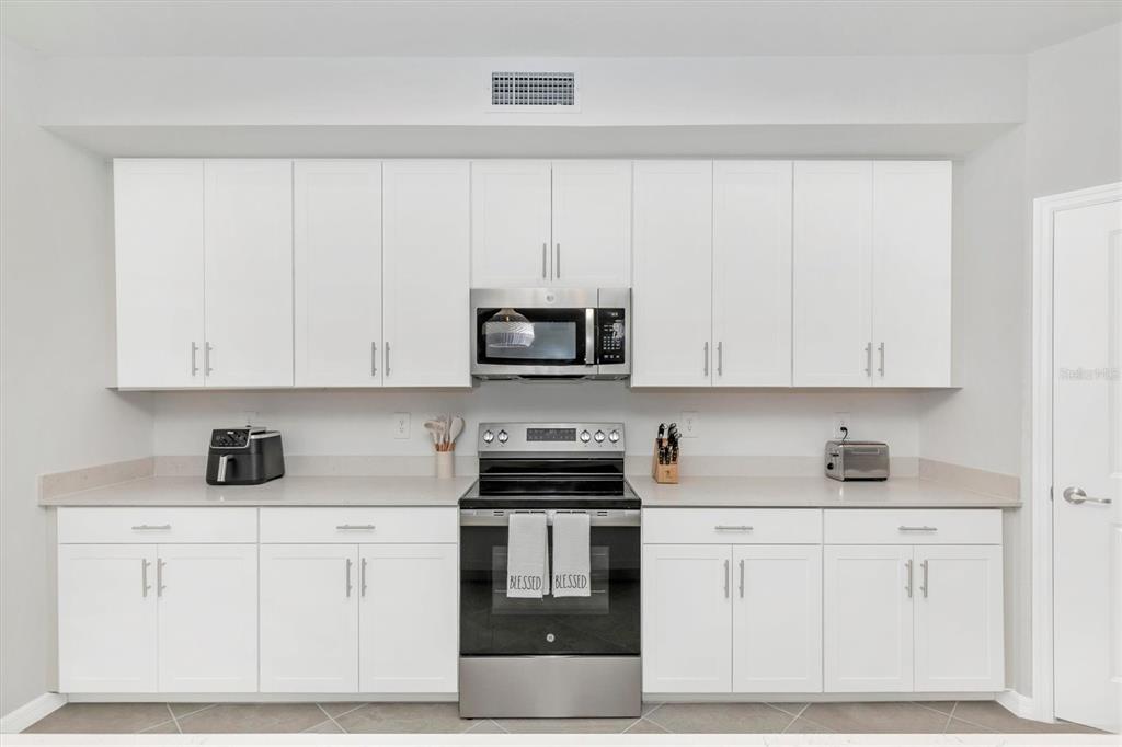 12625 Radiance Court, Unit 102 Venice, FL 34293 - Photo 14 of 99 a kitchen with white cabinets and a stove
