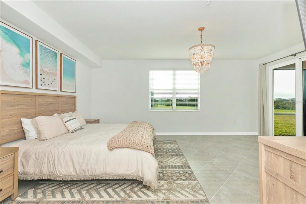 12625 Radiance Court, Unit 102 Venice, FL 34293 - Photo 32 of 99 a bedroom with a large bed and a chandelier