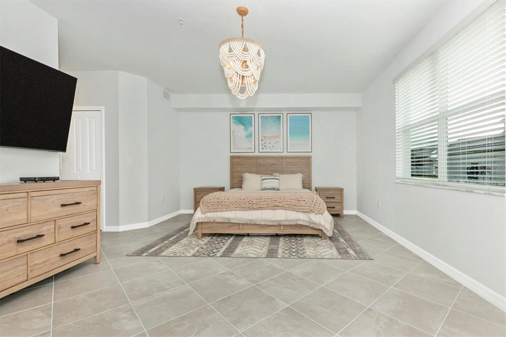 12625 Radiance Court, Unit 102 Venice, FL 34293 - Photo 33 of 99 a bedroom with a bed and a flat tv screen on dresser