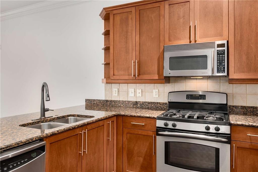 1055 Piedmont Avenue Northeast, Unit 114 Atlanta, GA 30309 - Photo 10 of 40 a kitchen with granite countertop a stove top oven microwave and cabinets
