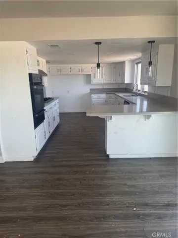 a kitchen with stainless steel appliances wooden floor and a refrigerator
