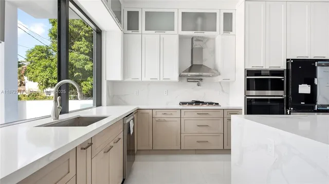 a kitchen with stainless steel appliances granite countertop white cabinets and a window