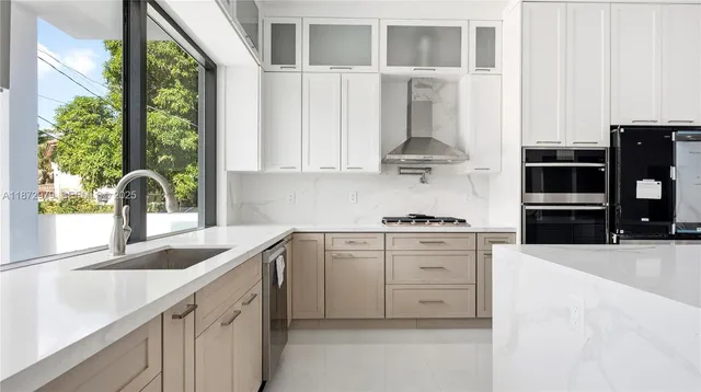 a kitchen with stainless steel appliances granite countertop white cabinets and a window