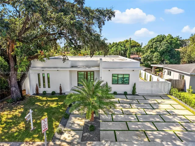 a view of a house with many windows next to a yard