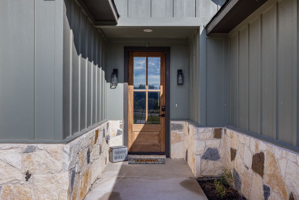 An inviting recessed entry features a wood and glass front door set against stone wainscoting.
