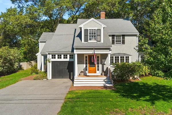 a front view of a house with a yard and trees