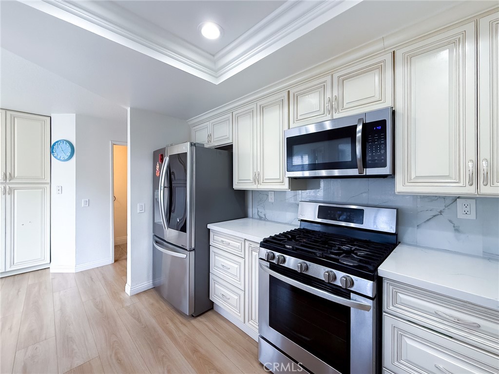 33 Wildflower Place Phillips Ranch, CA 91766 - Photo 21 of 49 a kitchen with stainless steel appliances a stove a microwave oven cabinets and a wooden floor