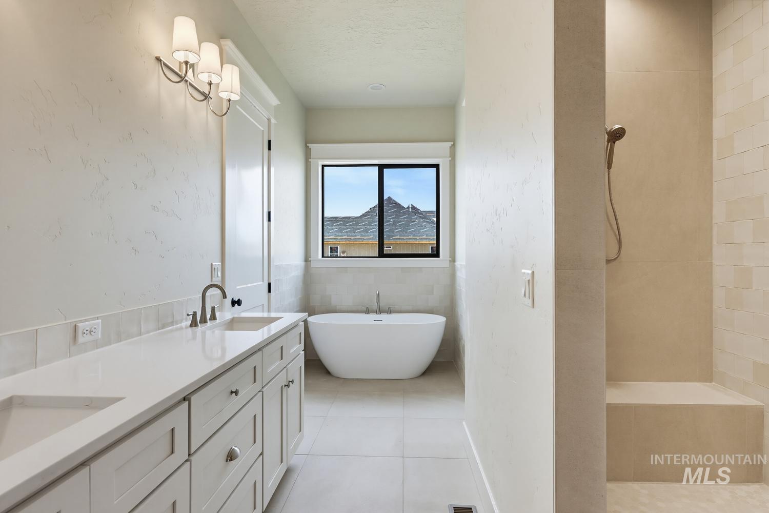 5054 Heritage Drive Marsing, ID 83639 - Photo 29 of 38 Contemporary bathroom featuring a freestanding soaking tub, a dual vanity with undermount sinks and white countertops, a walk-in shower with a built-in bench, and light-colored tile flooring