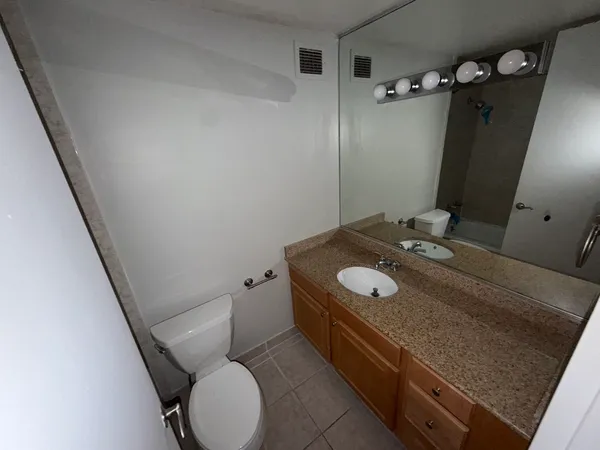 a bathroom with a granite countertop sink a toilet and mirror