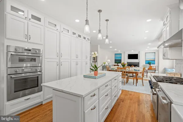 a kitchen with stainless steel appliances kitchen island granite countertop a stove top oven a sink dishwasher and a refrigerator with wooden floor