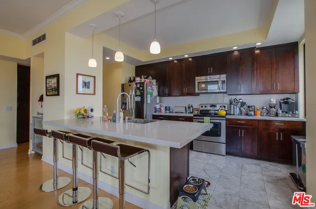 a kitchen with stainless steel appliances kitchen island granite countertop a table chairs sink and cabinets