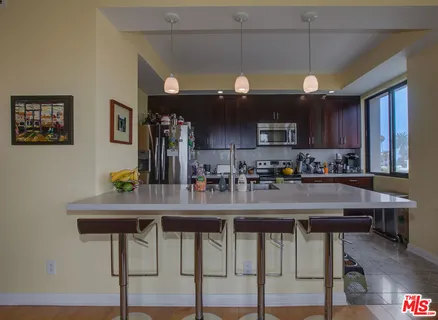 a kitchen with stainless steel appliances granite countertop a table chairs refrigerator and sink