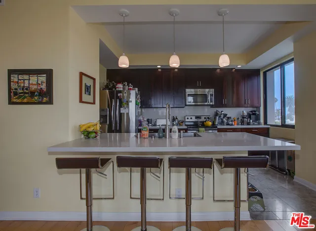 a kitchen with stainless steel appliances granite countertop a table chairs refrigerator and sink