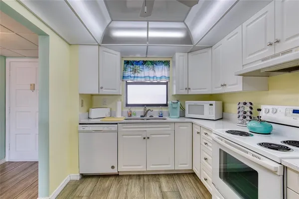 a kitchen with a sink dishwasher stove and white cabinets