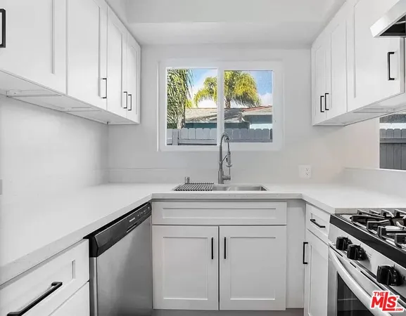 a kitchen with white cabinets and a window