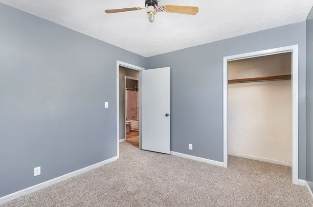 an empty room that has a window and a ceiling fan