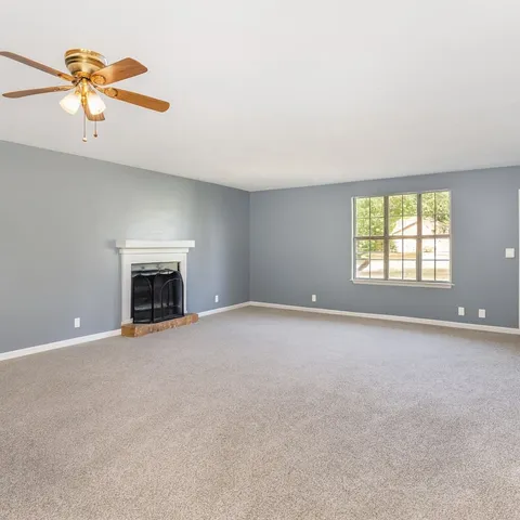 an empty room with windows and fireplace