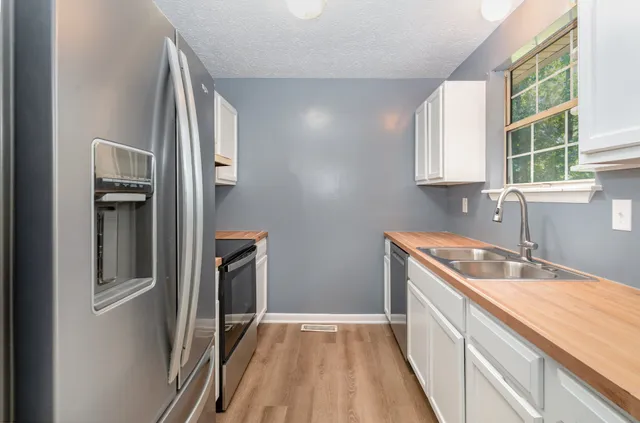 a kitchen with granite countertop a sink stove and refrigerator