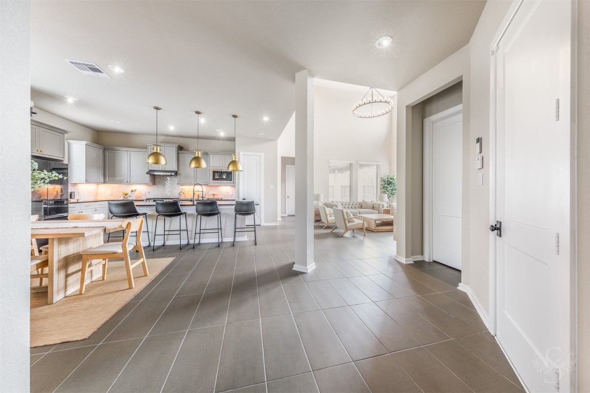 a living room with stainless steel appliances lots of white furniture wooden floor and a kitchen view