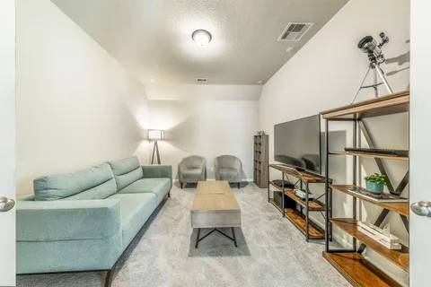 a living room with furniture a flat screen tv and a floor to ceiling window
