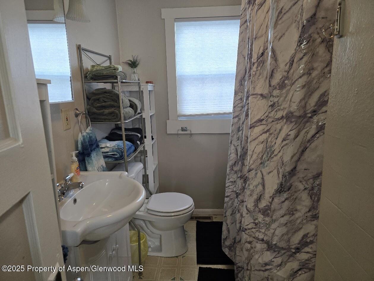830 Breeze Street Craig, CO 81625 - Photo 12 of 18 a bathroom with a toilet and a shower curtain
