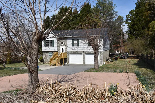 a front view of a house with a yard and large tree