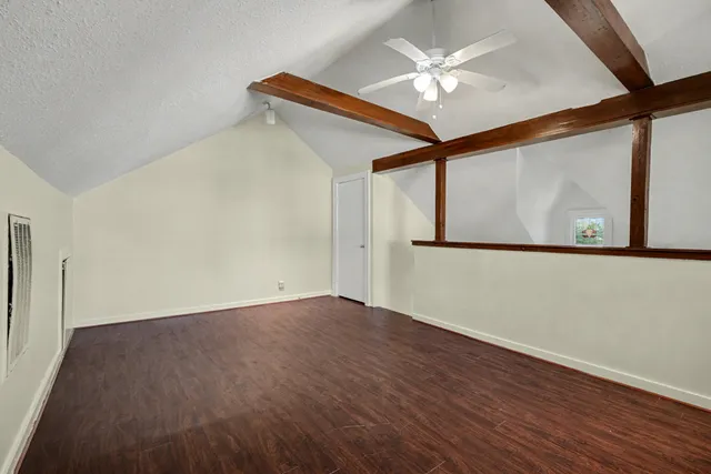 a view of an empty room with wooden floor and a chandelier fan