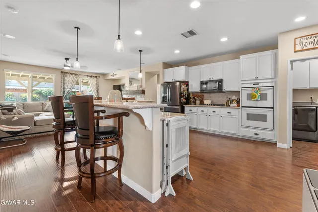 a kitchen with stainless steel appliances kitchen island granite countertop a table chairs and a refrigerator