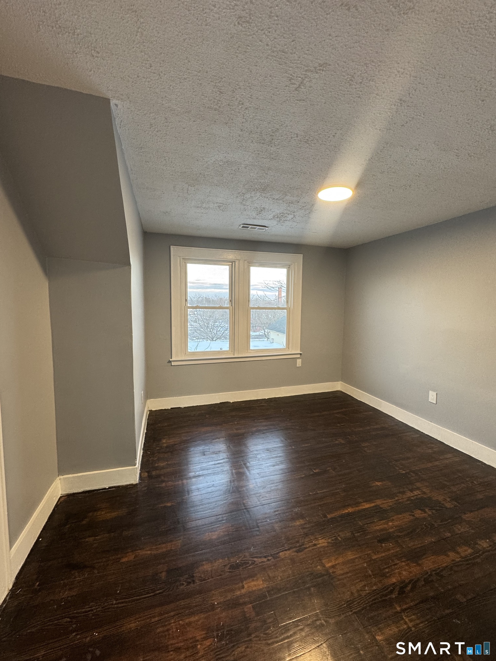 10 Lester Street, Unit 3 West Haven, CT 06516 - Photo 5 of 10 a view of an empty room with wooden floor and a window
