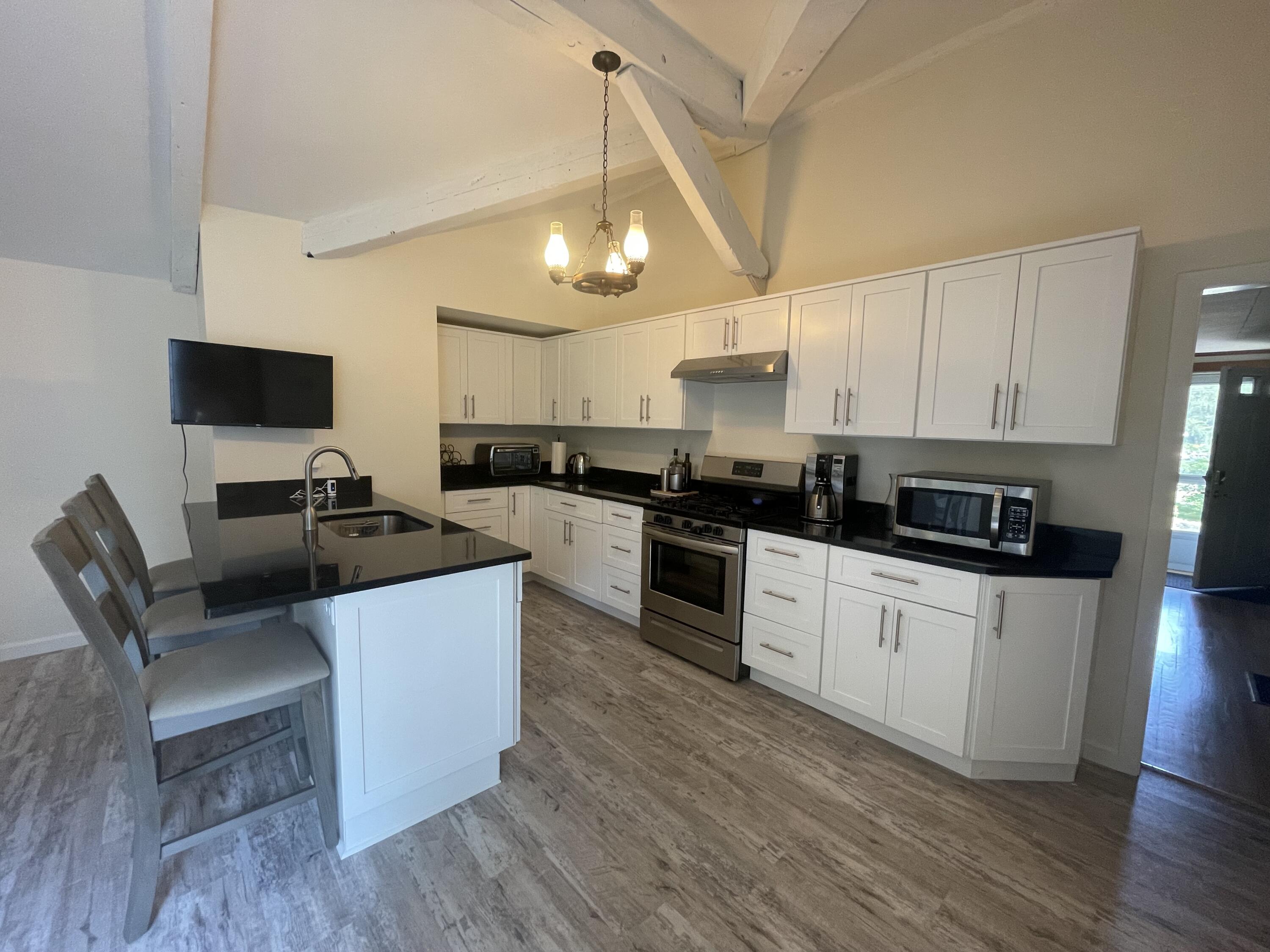 358 Strawberry Hill Road Centerville, MA 02632 - Photo 5 of 11 a white kitchen with wooden floors and stainless steel appliances