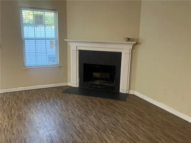 a view of an empty room with wooden floor fireplace and a window