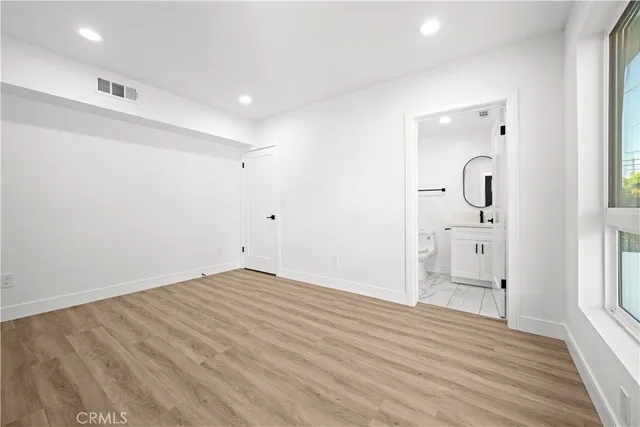 a view of empty room with wooden floor and window