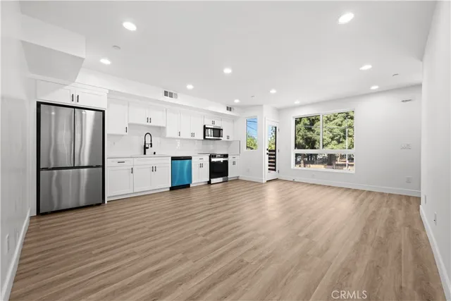 a view of kitchen with stainless steel appliances kitchen island wooden floor and window