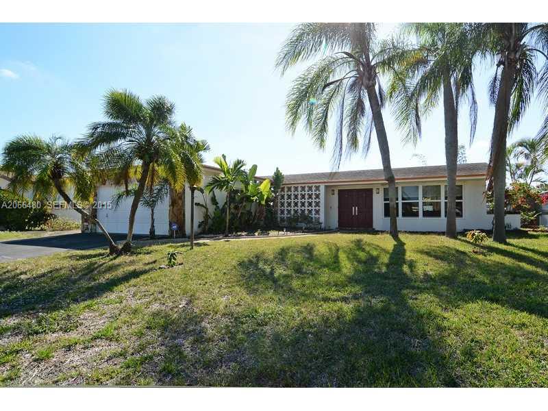 a view of a house with a yard and palm trees