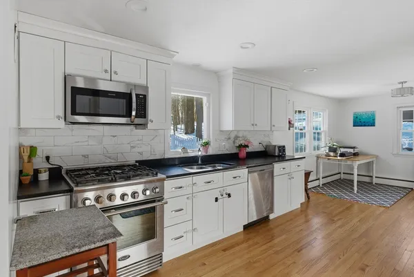 a kitchen with stainless steel appliances granite countertop a refrigerator a sink a stove and white cabinets