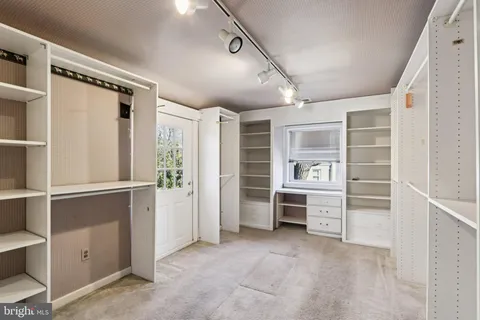 a view of a hallway with wooden floor and a bathroom