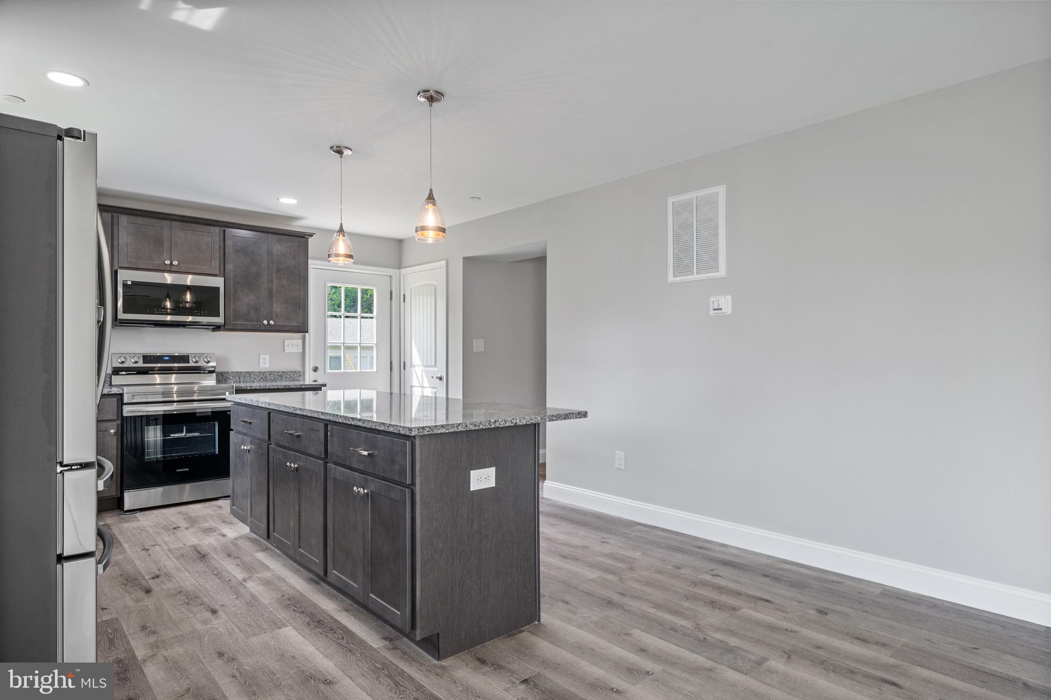 24215 Thistle Place Chaptico, MD 20621 - Photo 11 of 40 a kitchen with stainless steel appliances granite countertop a stove top oven a sink dishwasher and a refrigerator with wooden floor