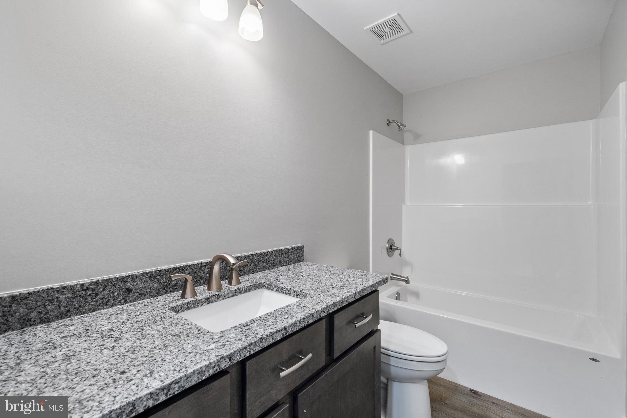 24215 Thistle Place Chaptico, MD 20621 - Photo 28 of 40 a bathroom with a granite countertop sink a toilet and bathtub