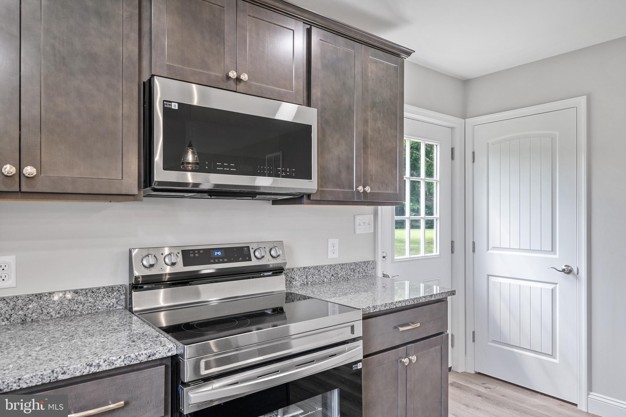 24215 Thistle Place Chaptico, MD 20621 - Photo 10 of 40 a kitchen with stainless steel appliances granite countertop a stove and a microwave