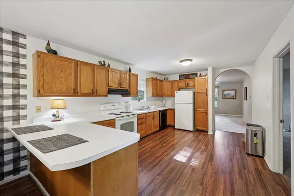 a kitchen with a refrigerator a sink dishwasher stove and wooden cabinets
