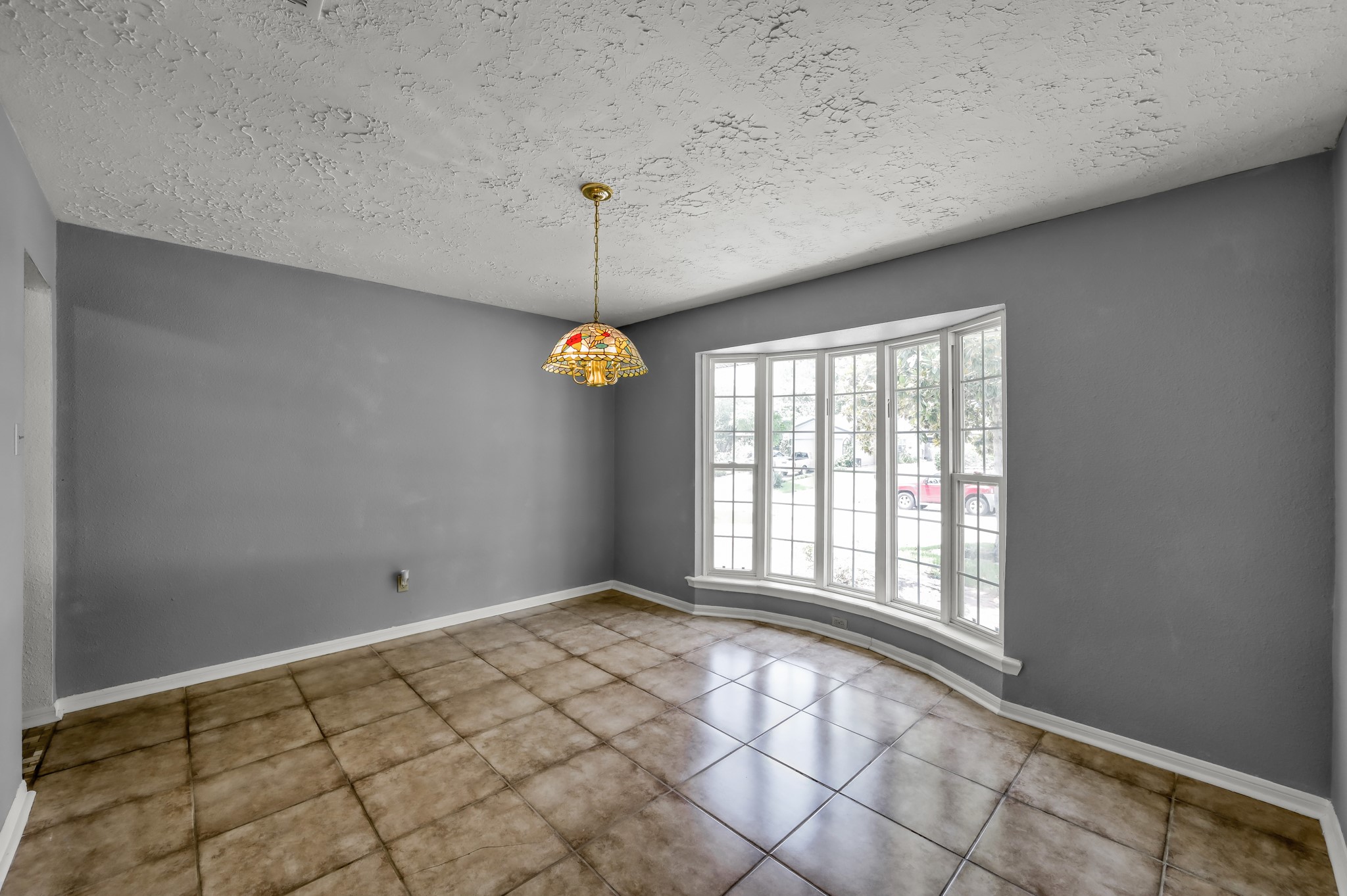 4314 Enchantedgate Drive Spring, TX 77373 - Photo 6 of 47 This room features a large bay window allowing plenty of natural light, gray walls, and tiled flooring, creating an inviting and spacious atmosphere. A decorative hanging light fixture adds charm to the space.