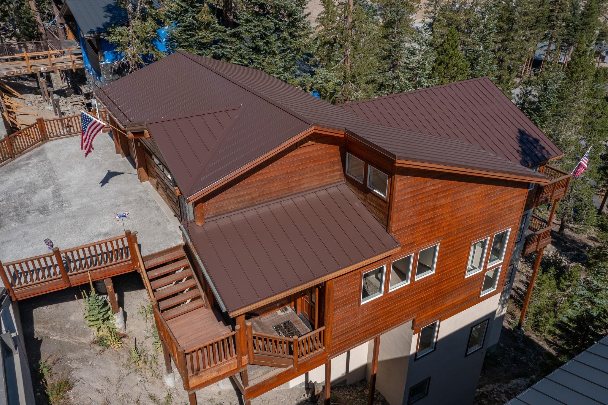 492 John Muir Road Mammoth Lakes, CA 93546 - Photo 29 of 33 Wood-sided exterior with a brown metal roof, featuring multiple windows, and a multi-level deck system with railings